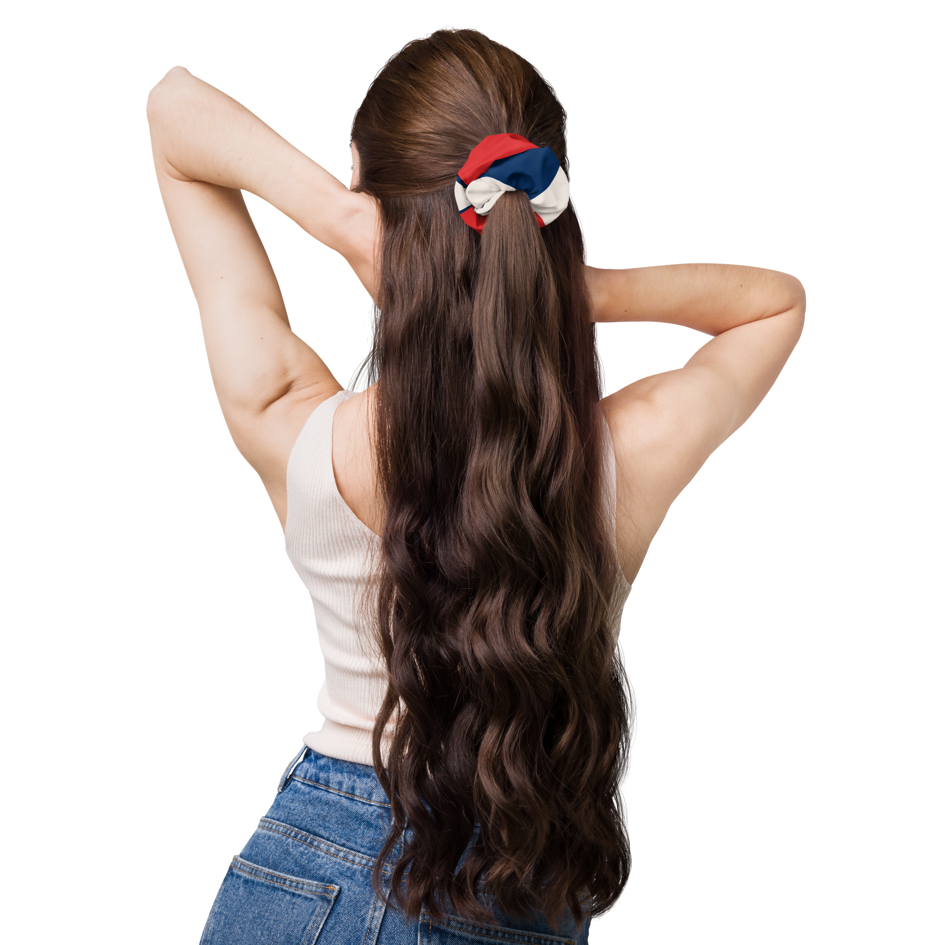Woman with long wavy hair tied back with a scrunchie, wearing a white top and blue jeans on a white background