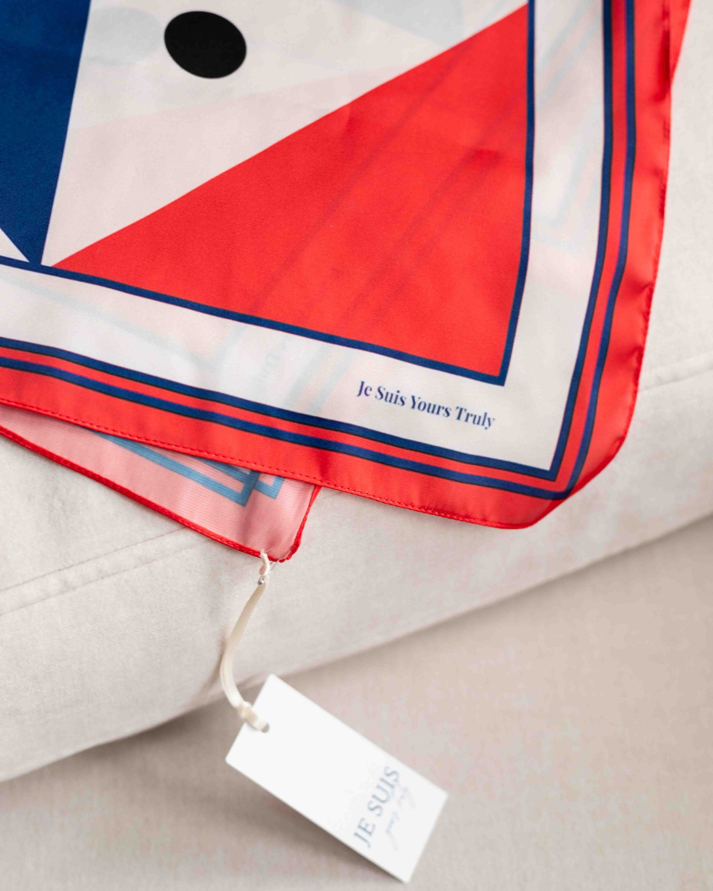 Red, white, and blue patterned scarf with a visible brand tag on a neutral background