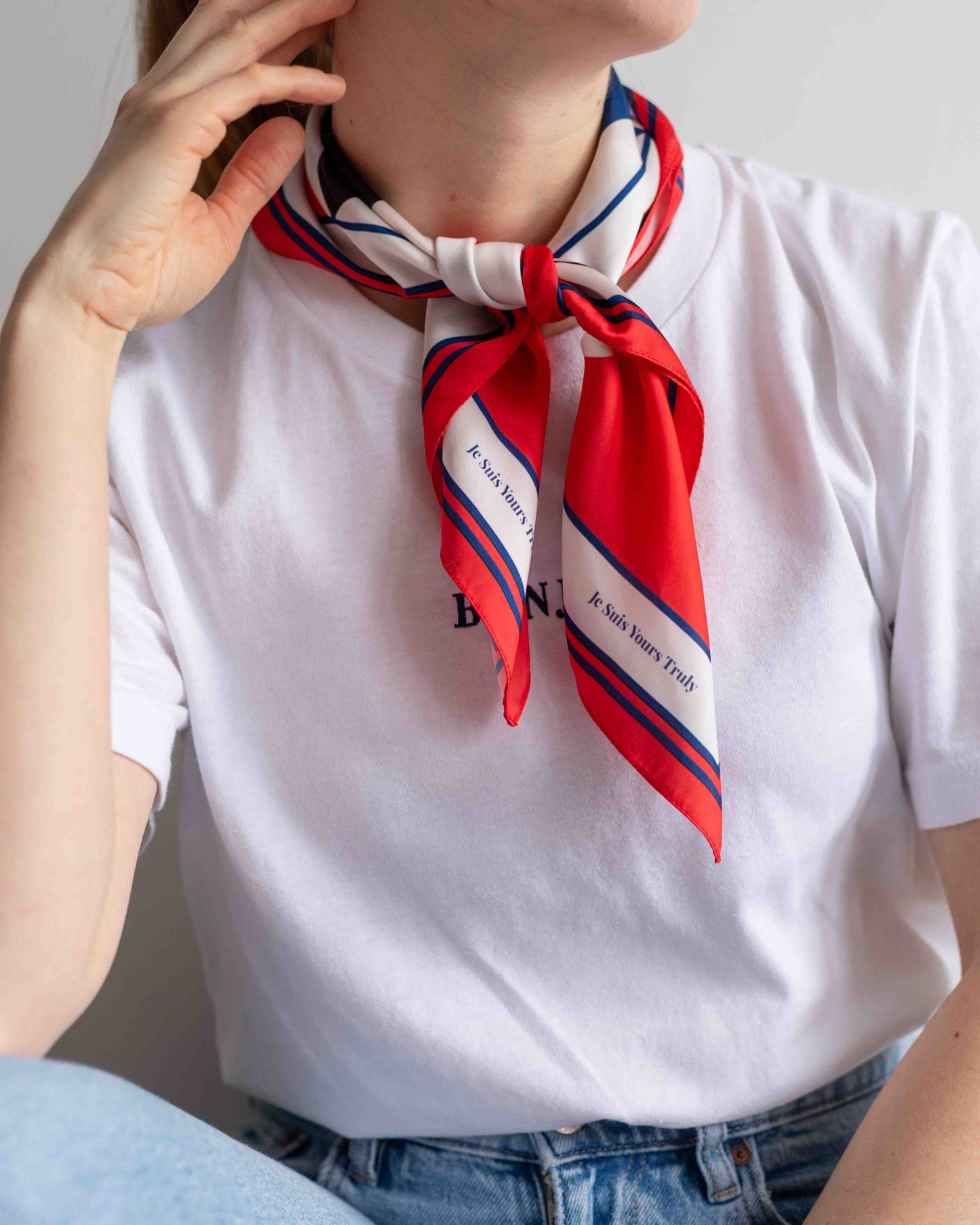 Person wearing a red and blue striped scarf with text on a white shirt.