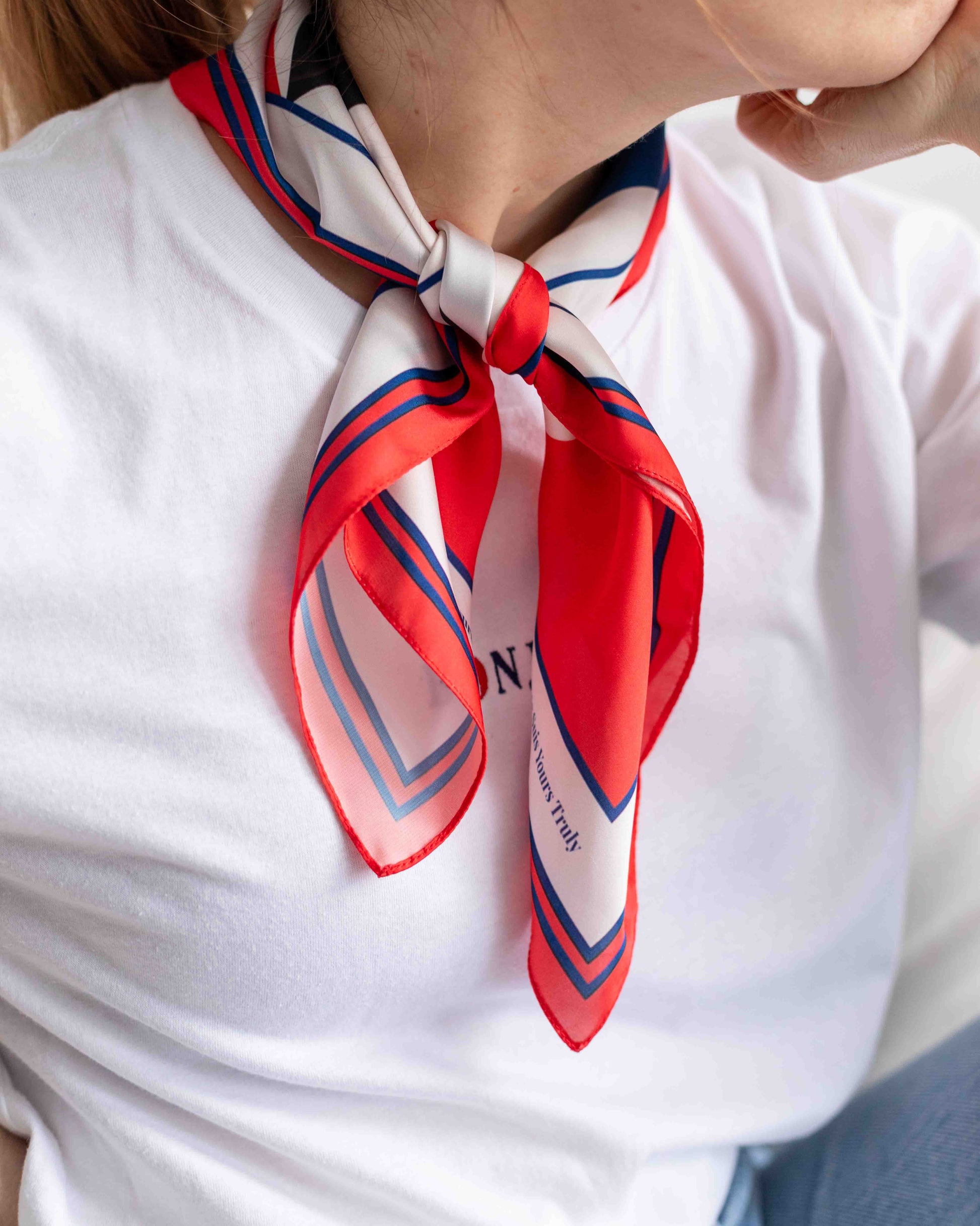 Person wearing a red and white striped scarf with a visible brand logo.