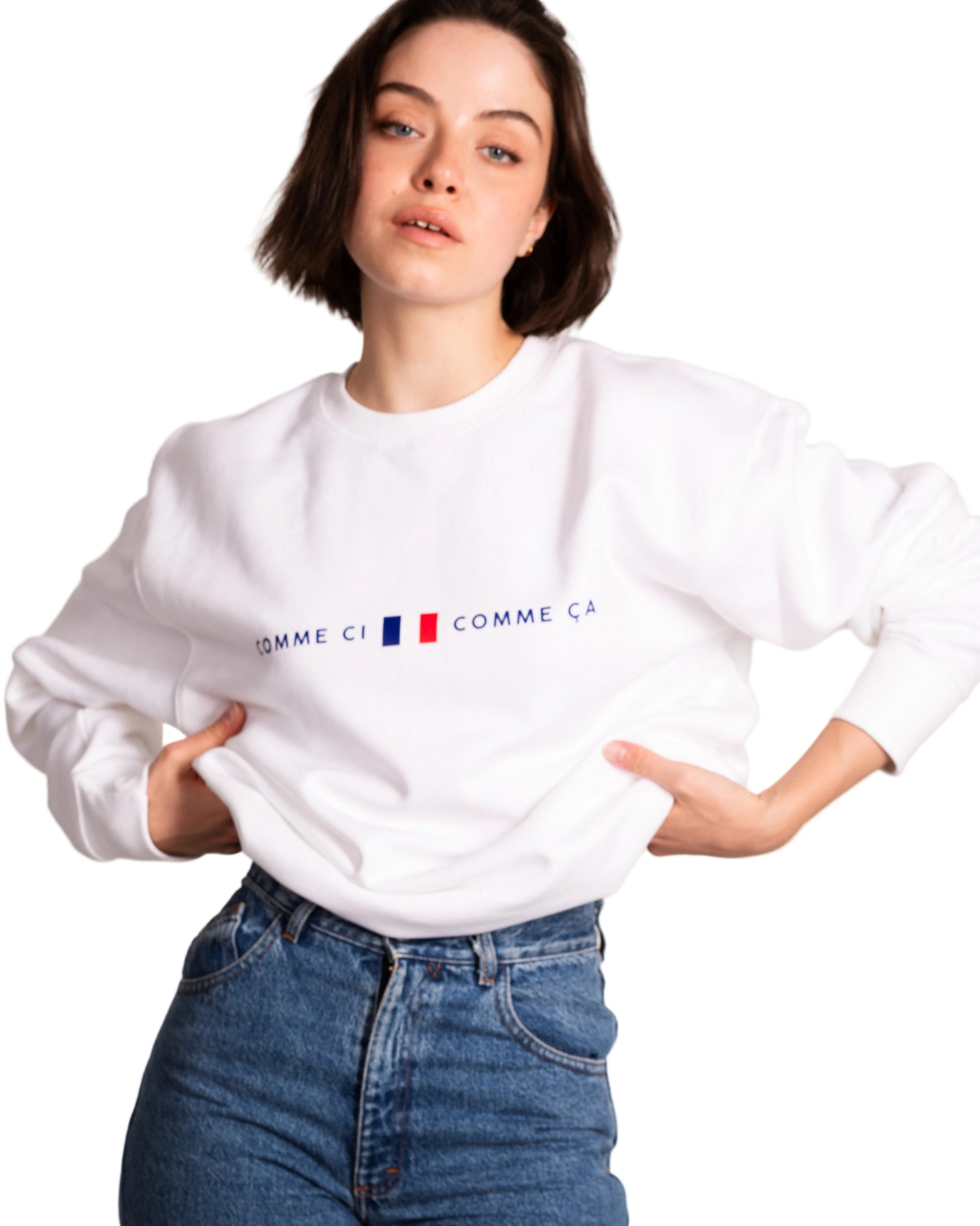 Person wearing a white sweatshirt with a logo, standing against a plain background