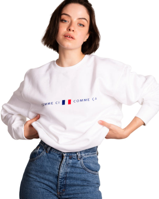 Person wearing a white sweatshirt with a logo, standing against a plain background