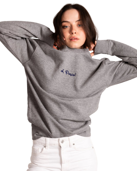 Person wearing a gray sweatshirt with 'oh paris' text on a white background