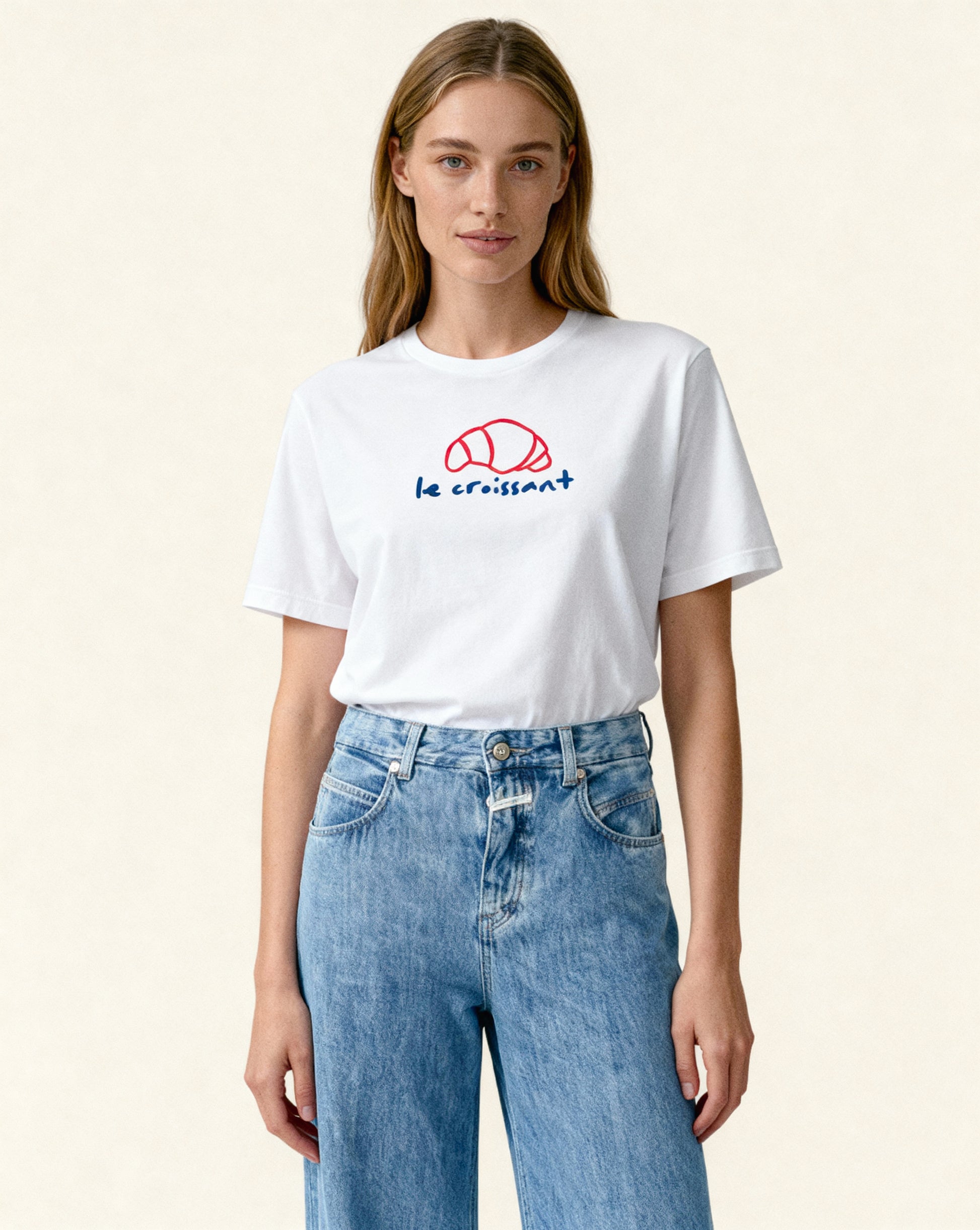 Person wearing a white t-shirt with a logo and text, standing against a plain background