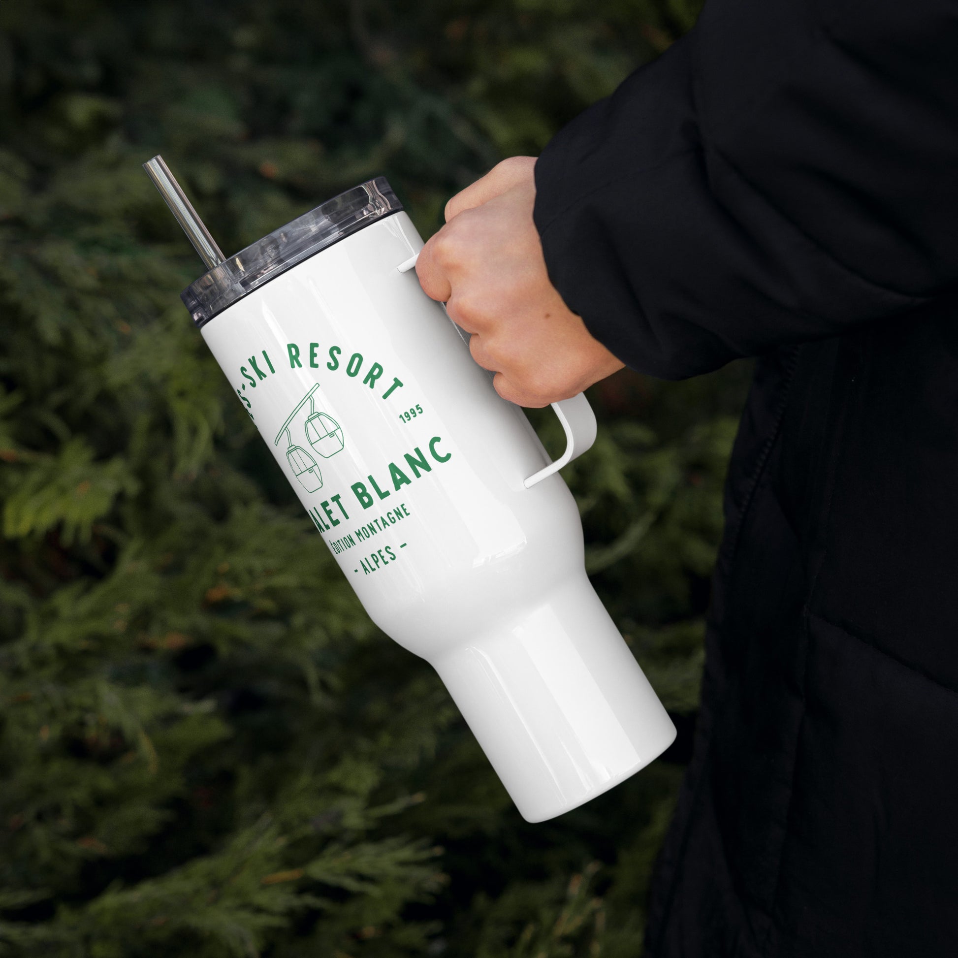 White tumbler with green text held by a person against a green background
