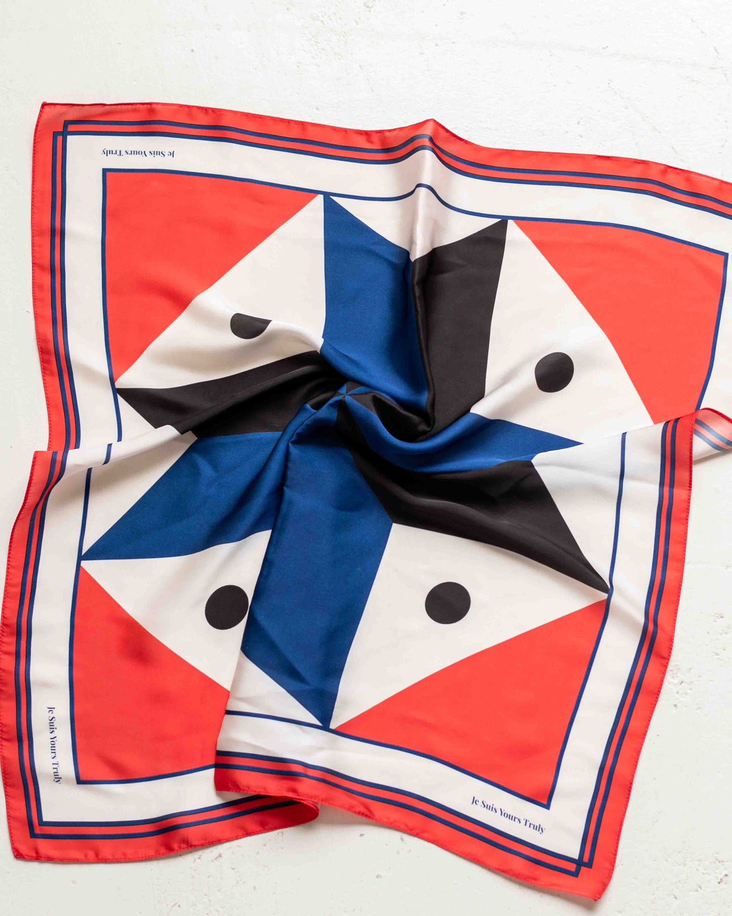 Colorful geometric patterned scarf with red, blue, black, and white on a light background