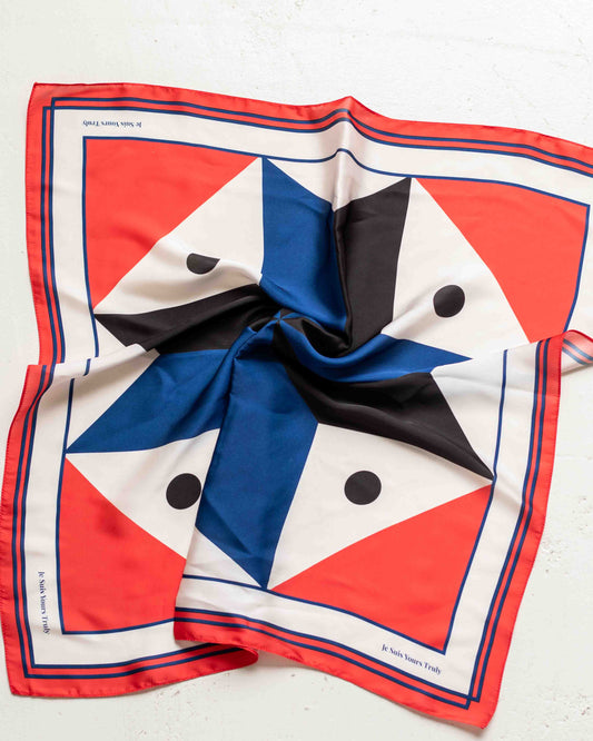 Colorful geometric patterned scarf with red, blue, black, and white on a light background